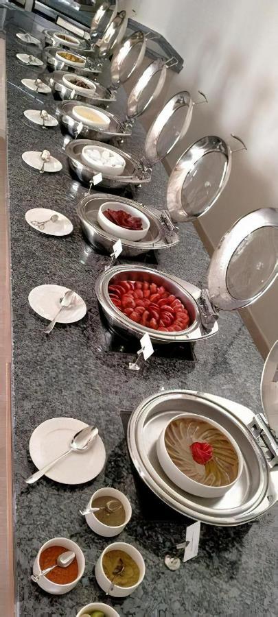 עיין סוחנה Tolip Resort El Galala Majestic מראה חיצוני תמונה The photo shows a buffet setup featuring multiple metal serving trays on a dark granite countertop. One tray contains circular slices of food, possibly sausages or a similar dish, while another bowl holds what appears to be red food items, though it'